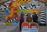 La regidora Montserrat Flores (centre) i dues persones responsables del Casal de Joves davant un mural de 